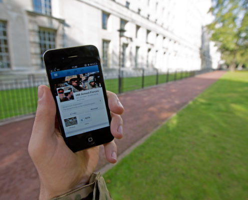 A serviceman accesses social media channels using a smart phone, outside MOD Main Building in London.