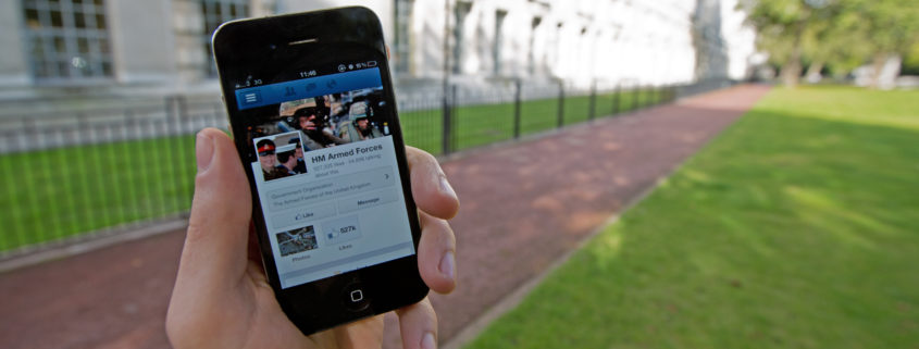 A serviceman accesses social media channels using a smart phone, outside MOD Main Building in London.